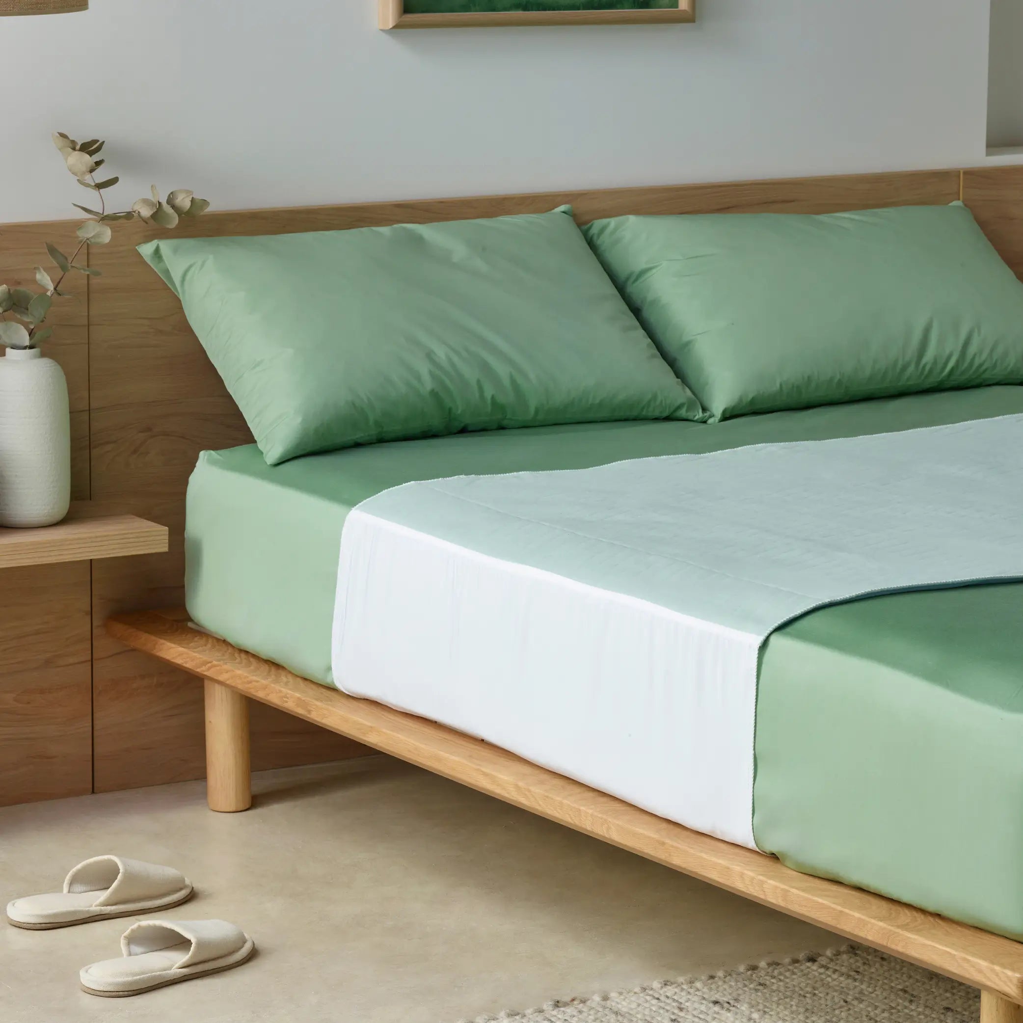 Boss Waterproof Bed Pad, also known as Kylie bed bad on a stylish bed with sage green sheets. Designed for superior incontinence protection, this washable, reusable bed pad keeps mattresses dry while providing a soft, breathable, and comfortable sleep surface.