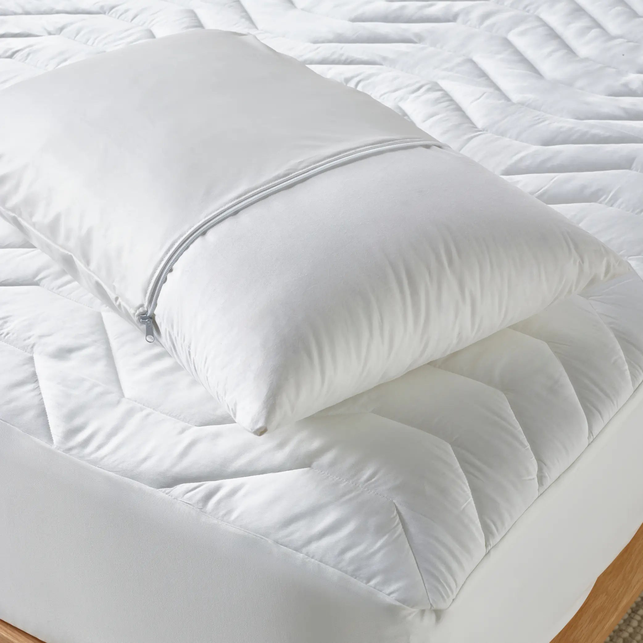 Close-up of a white pillow encased in the DuraTherme Waterproof Pillow Protector with a secure zip closure. This hypoallergenic, breathable, and waterproof pillow cover provides ultimate protection against spills, dust mites & allergens.