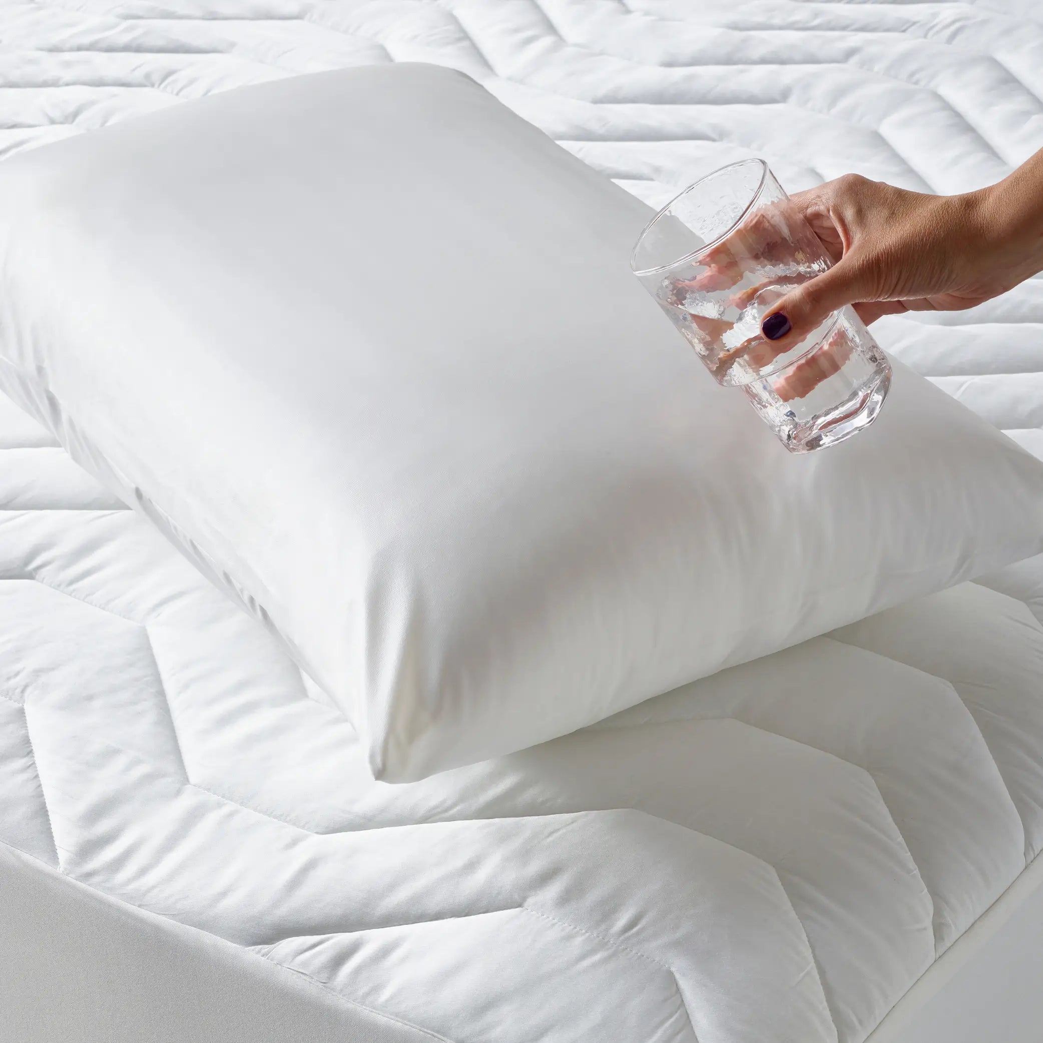 Hand pouring water on the Duratherme Waterproof Pillow, demonstrating its liquid-resistant, hypoallergenic protection. This premium pillow protector ensures a dry, breathable, and comfortable sleep experience while safeguarding against spills, dust mites, and allergens.