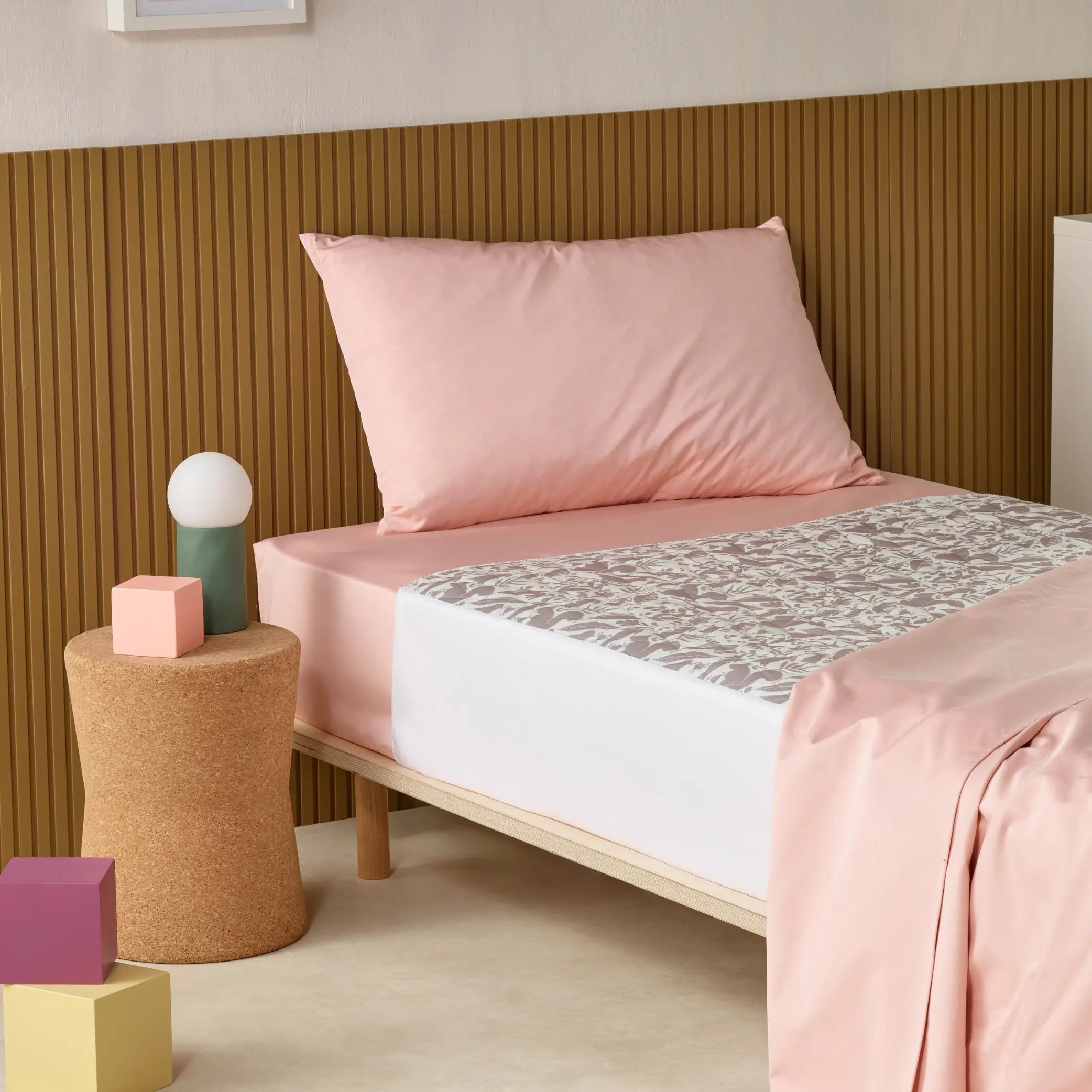 Children’s waterproof absorbent bed pad known as kylie bed pad with a soft, breathable design, placed on a single bed with pastel pink sheets. This reusable, washable incontinence bed protector provides leak-proof mattress protection for toilet training and night-time accidents.