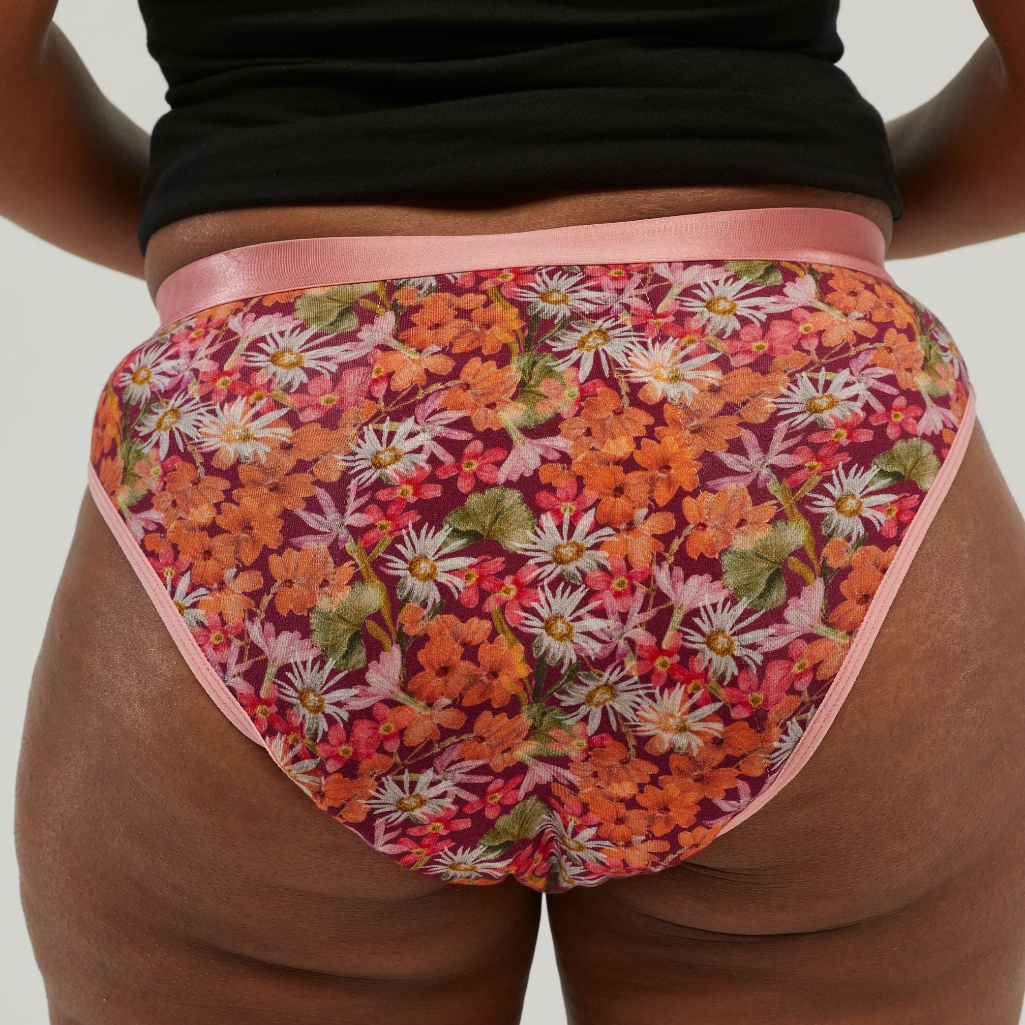 Back view of waterproof incontinence hipster underwear featuring a vibrant floral print and soft pink trim. Designed for discreet leak protection and all-day comfort.